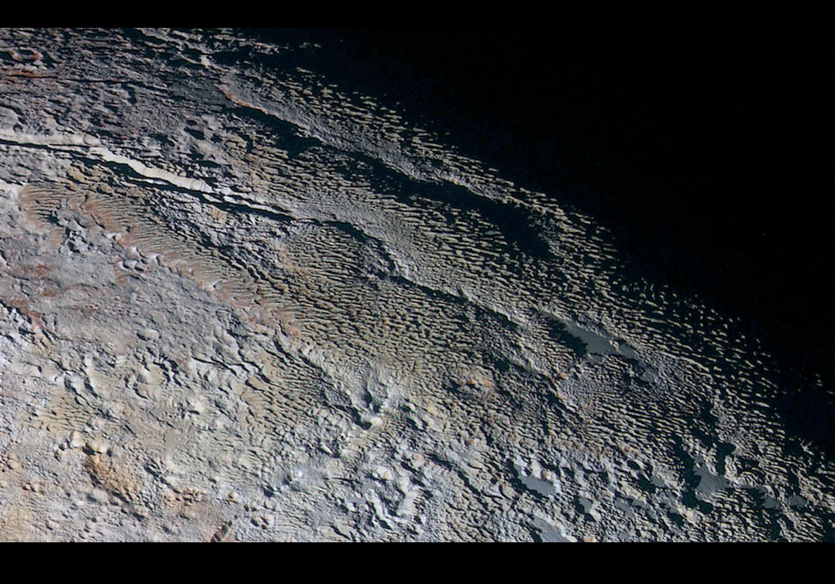 A New Horizons image, about 530 km/330 miles across, showing rounded and bizarrely textured mountains (the Tartarus Dorsa) that rise up along Pluto’s day-night terminator. There are intricate patterns of blue-gray ridges with reddish material in between. Resolution is about 1.3 km/0.8 miles. Credit: NASA/JHUAPL/SWRI